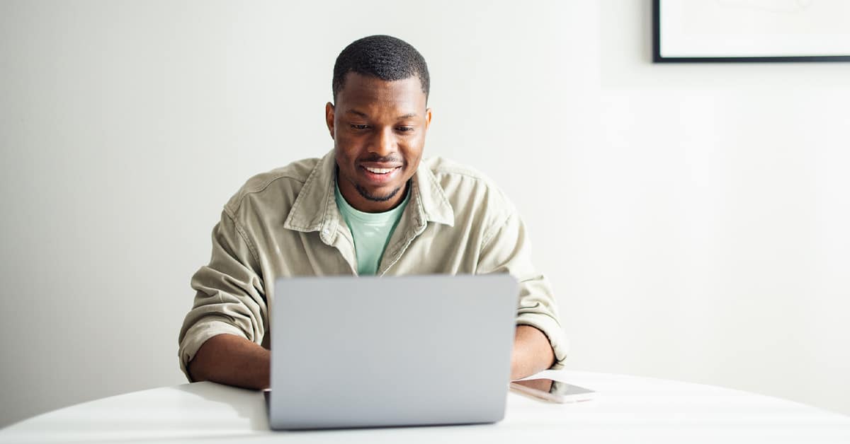 a man sitting at a table using a laptop computer